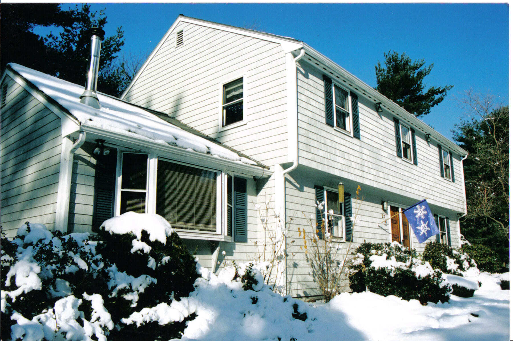Before image of white colonial home in the snow.