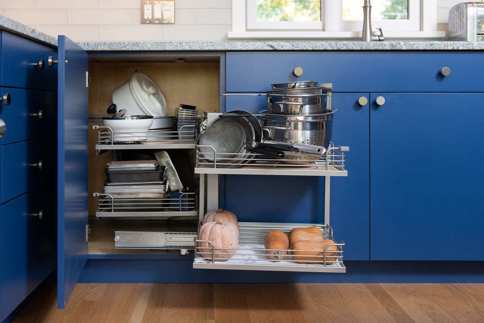 A modern pull-out kitchen cabinet with metal racks for cookware and storage, designed for functionality