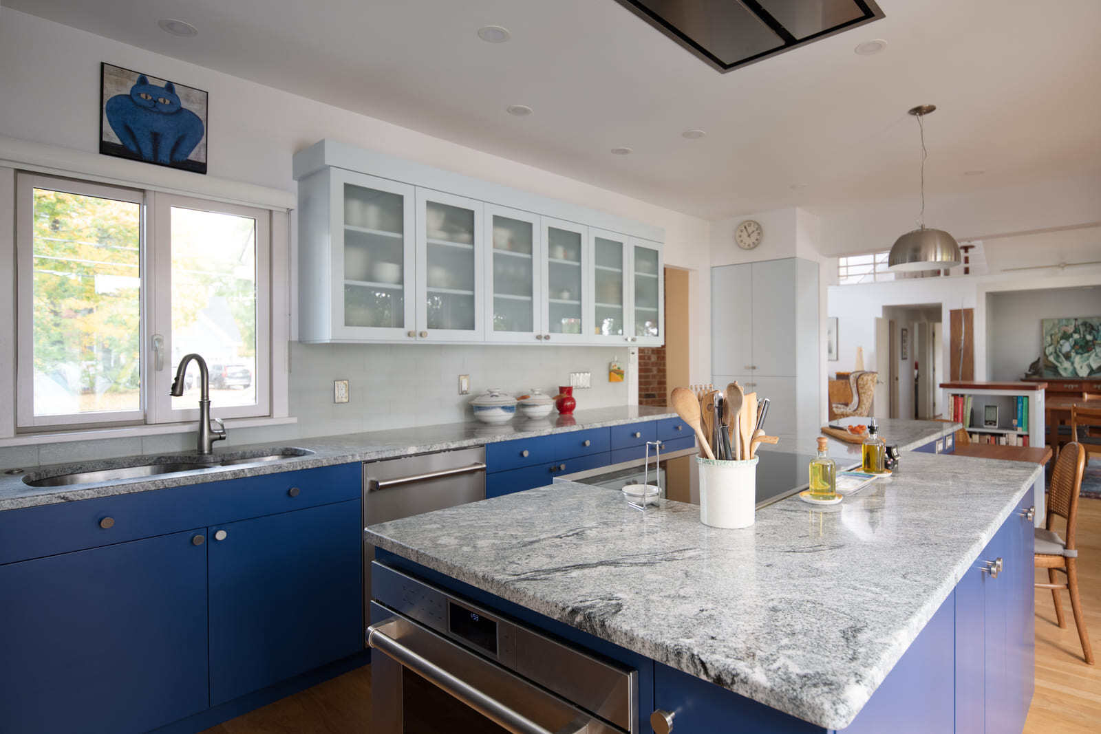 A well-lit kitchen with modern pendant lighting, large windows, and a combination of light and dark cabinetry