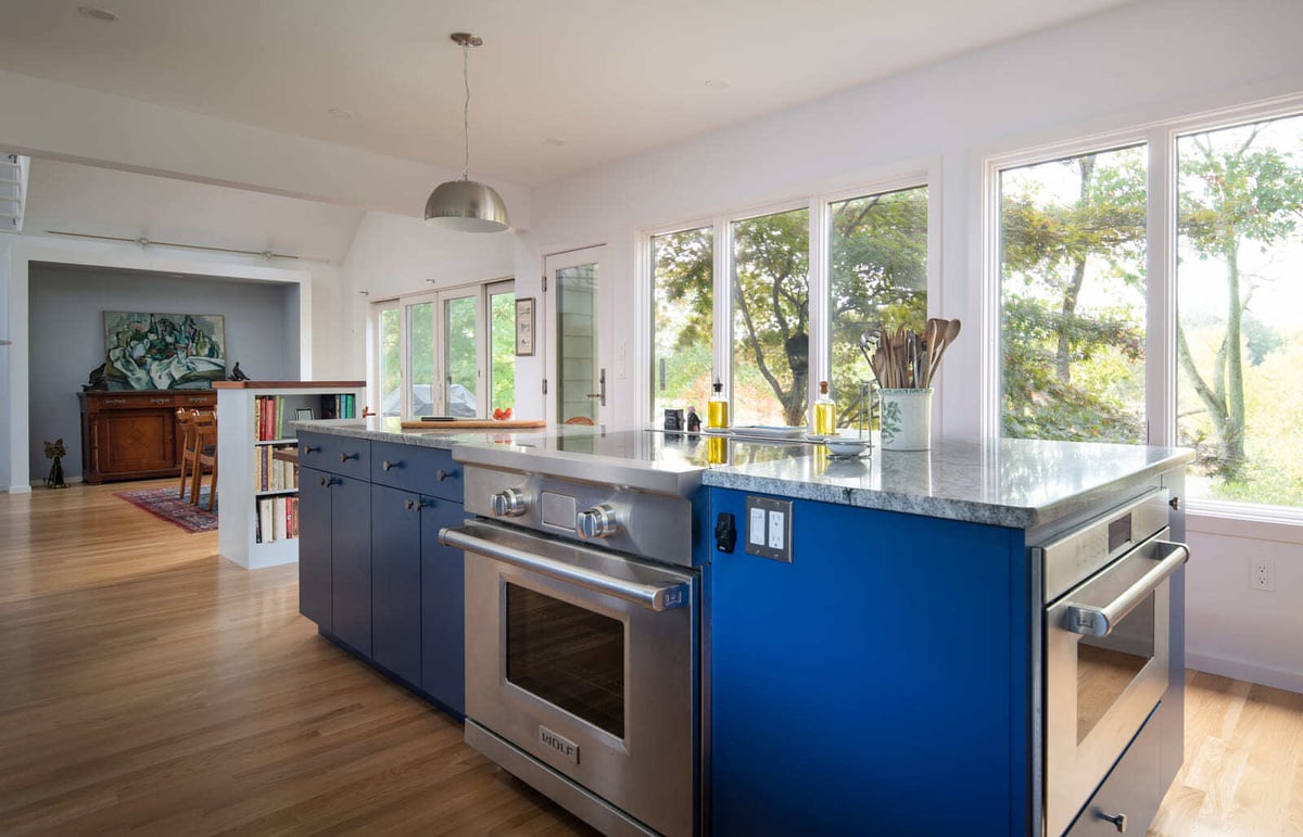 Custom kitchen remodel featuring a large island with stone countertops, high-end appliances, and floor-to-ceiling windows