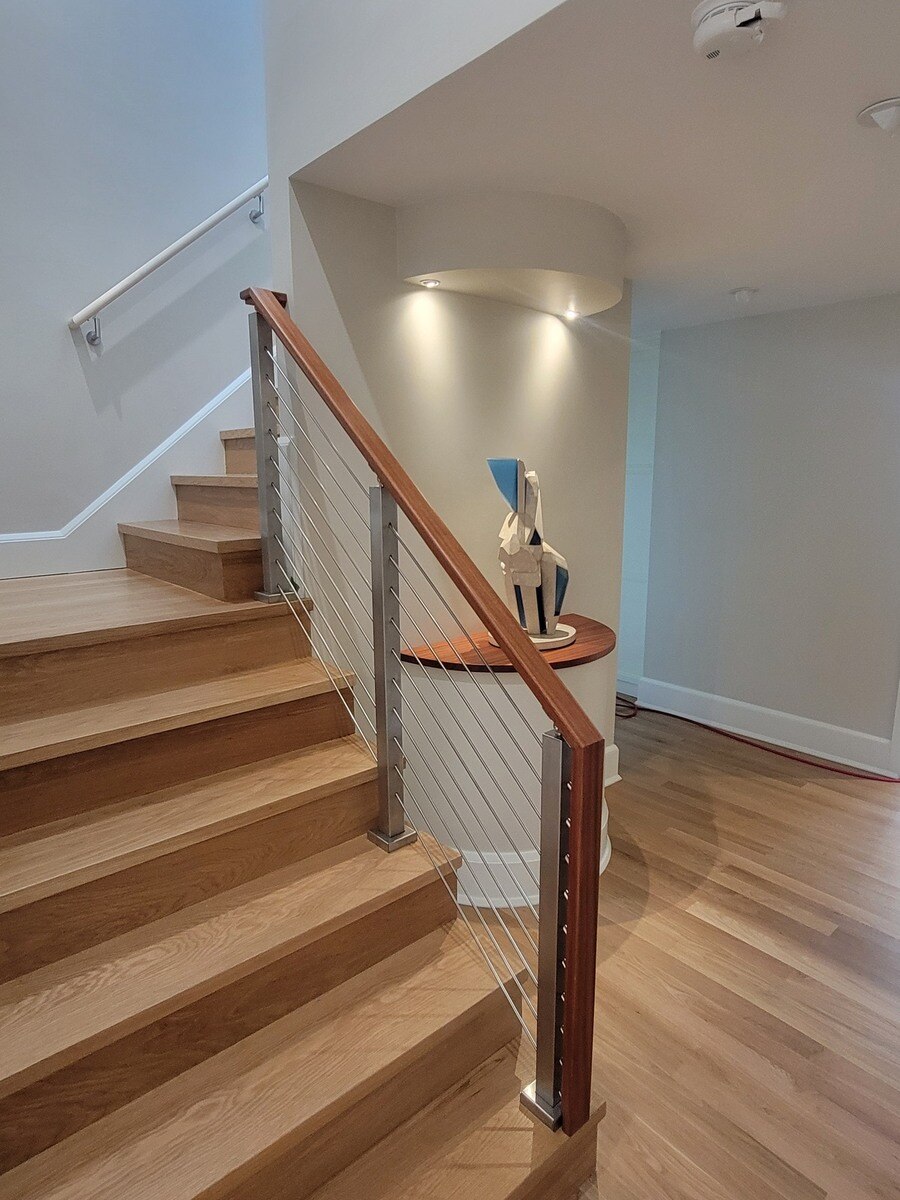 A modern staircase with wooden treads, sleek metal railings, and an art niche, part of a Frankel remodel in Acton, MA