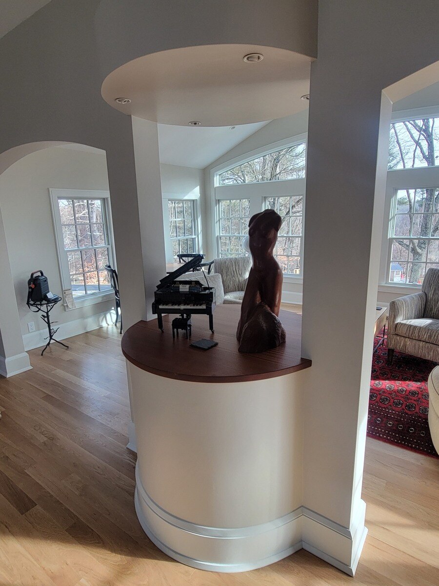A stylish built-in display featuring a sculpted wood figure and a miniature grand piano, part of a Frankel remodel in Acton, MA