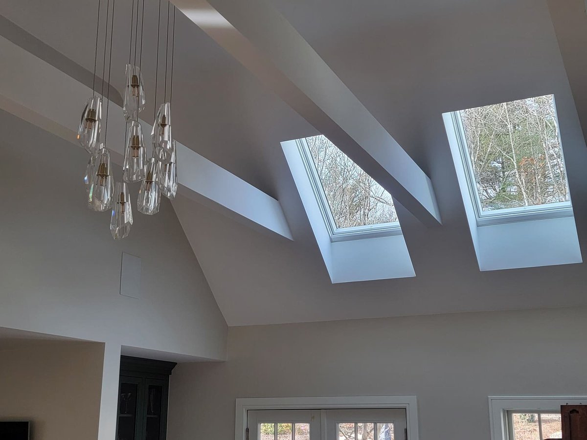 A vaulted ceiling with a contemporary glass chandelier and large skylights, allowing natural light to flood the living space in a Frankel remodel