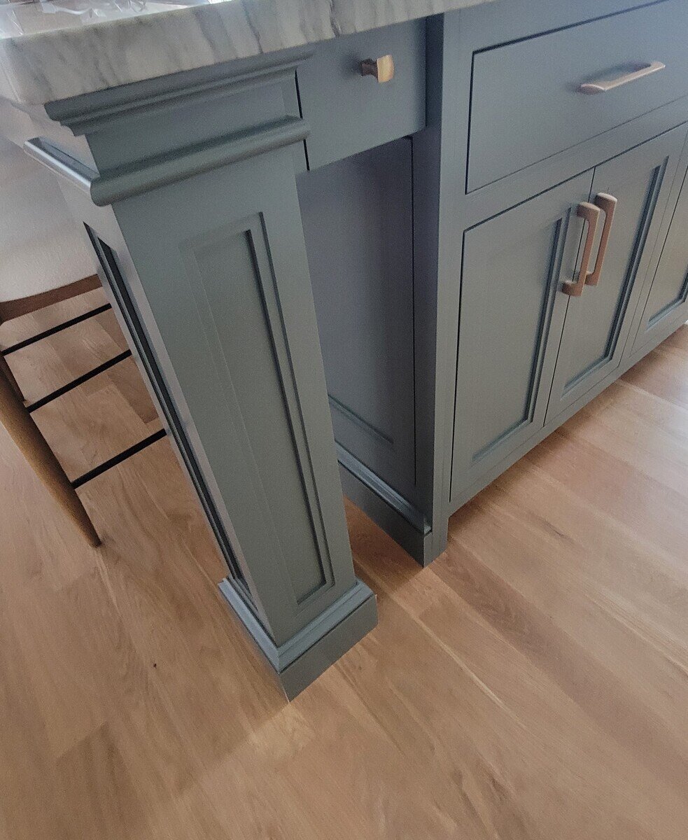 Close-up of a kitchen island’s leg detailing, showcasing classic cabinetry craftsmanship and elegant brass hardware