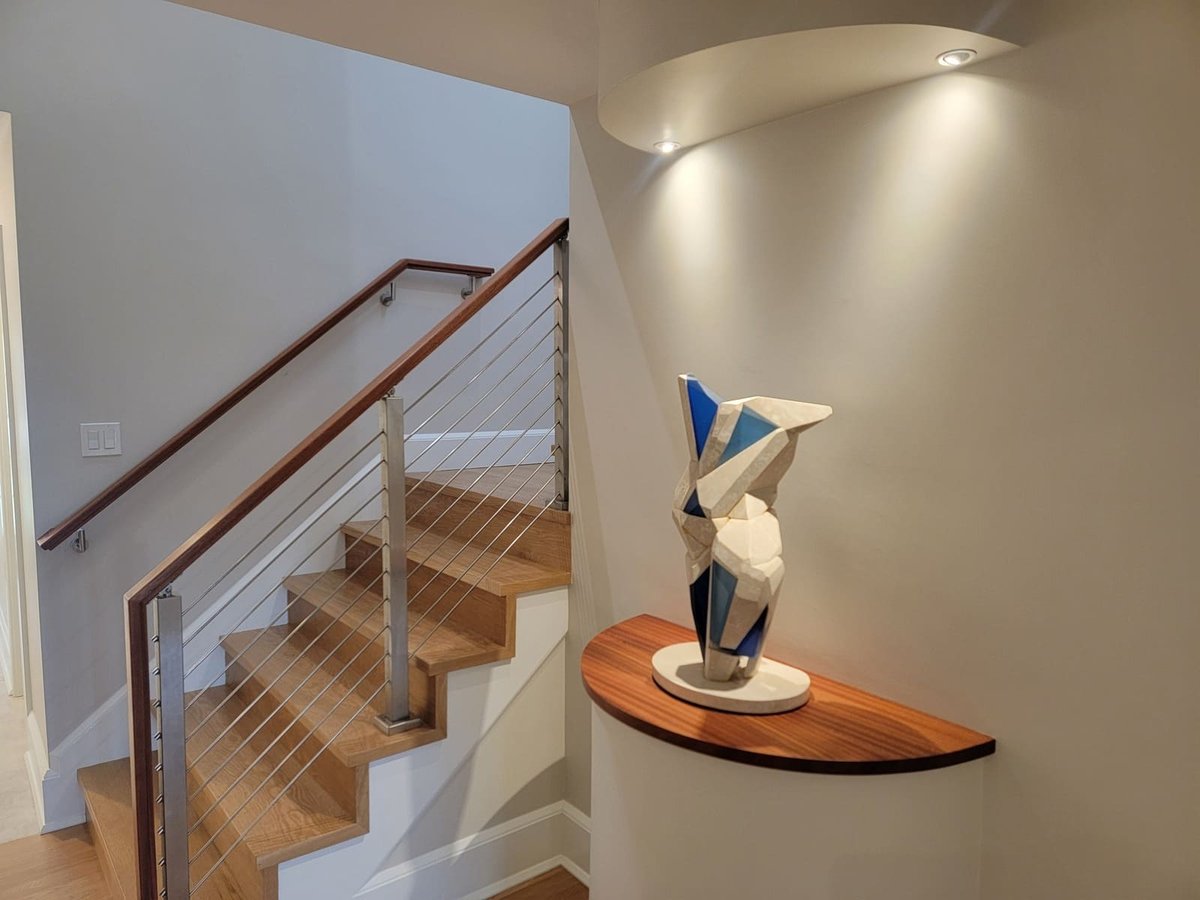 Contemporary staircase with steel railings and a sculpted blue and white ceramic piece in a built-in display alcove