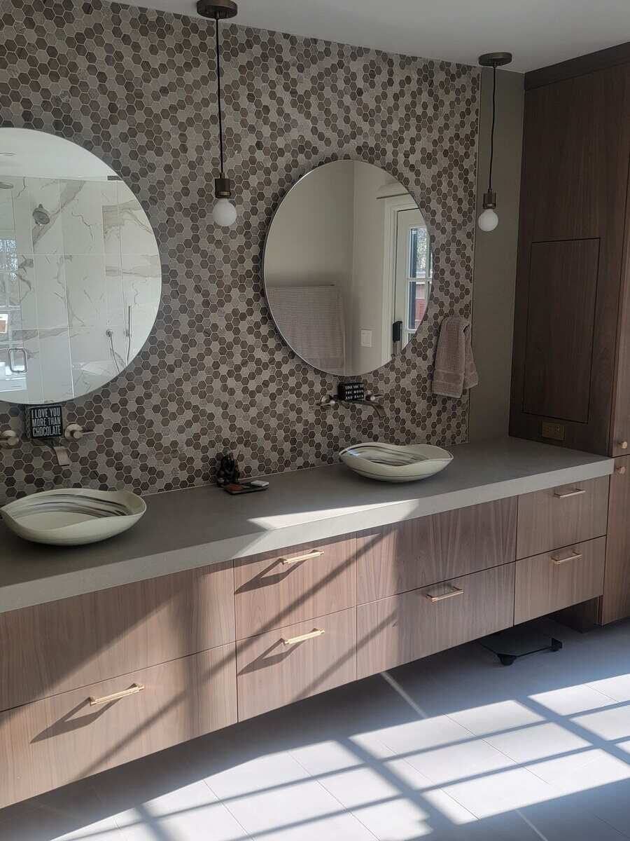 Dual sink bathroom vanity with warm wood cabinetry and modern lighting, bringing elegance to a home renovation in Acton, MA
