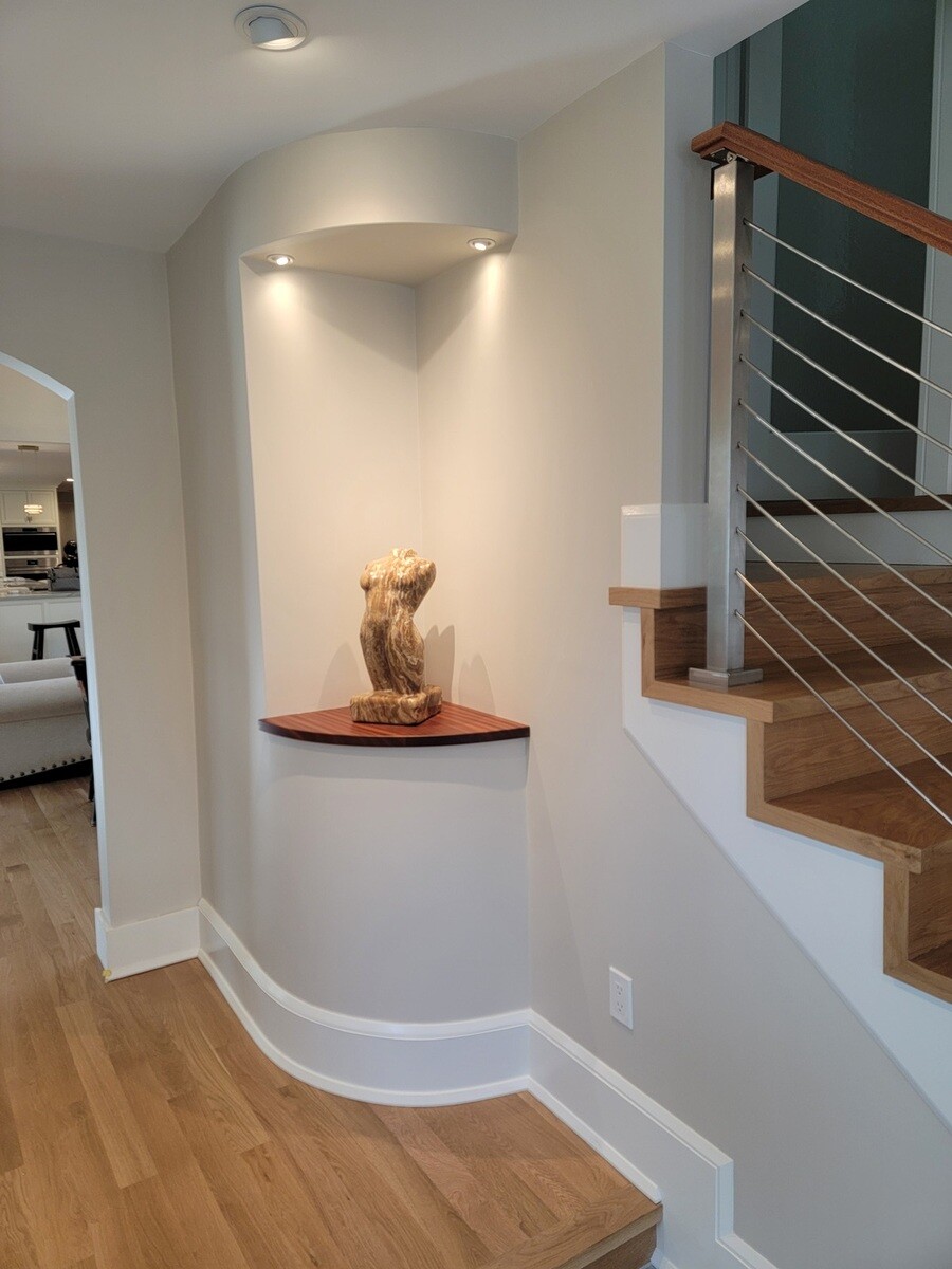 Elegant built-in display nook with soft lighting and a wood sculpture, designed by Thomas Buckborough & Associates