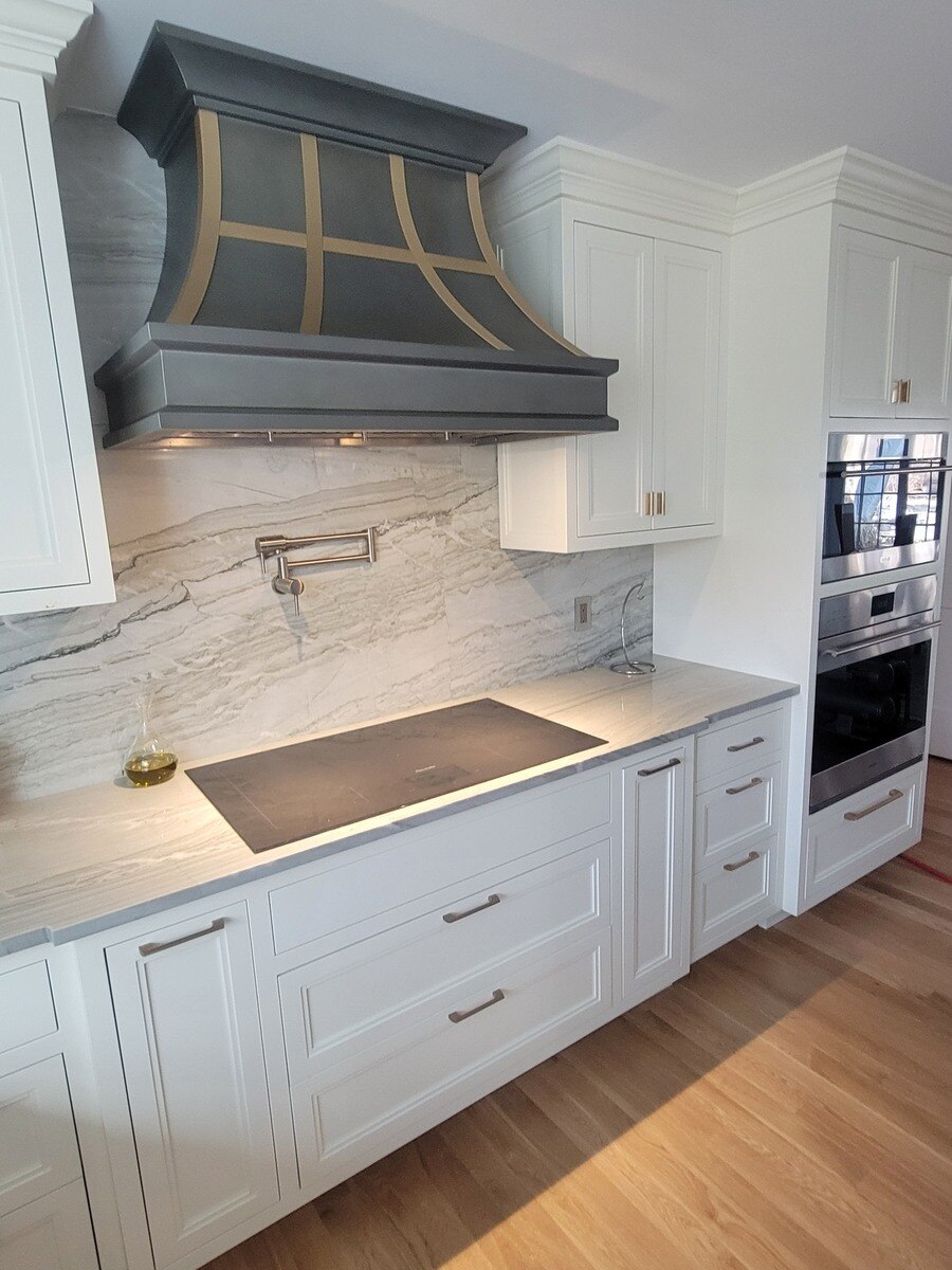 Elegant kitchen design with a bold black and gold range hood, sophisticated countertops, and built-in appliances