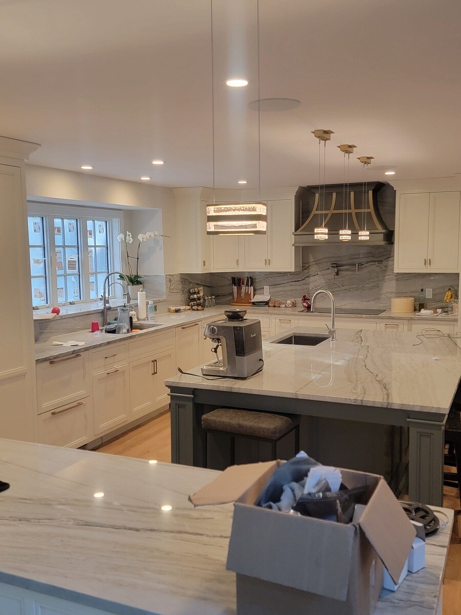 Luxurious white and gray kitchen with a statement range hood and pendant lighting, part of a Frankel remodel in Acton, MA