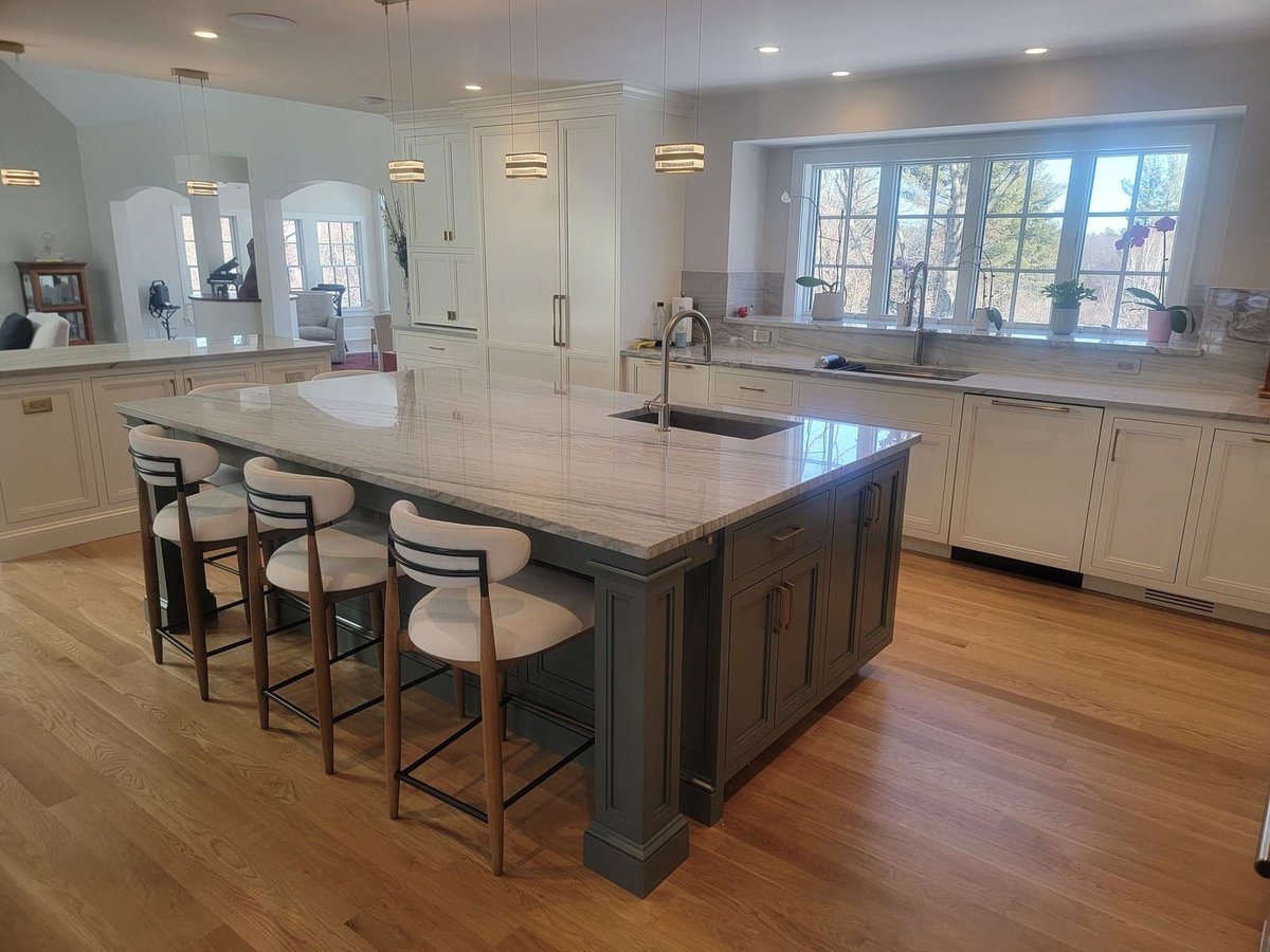 Sleek kitchen renovation in Acton, MA, featuring a spacious marble island, custom cabinetry, and stylish pendant lighting by Thomas Buckborough & Associates