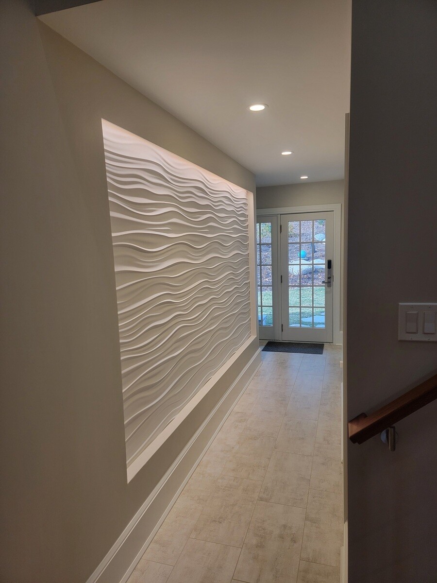 Stylish hallway design with a sculpted white wall and soft ambient lighting, adding texture and depth to the space