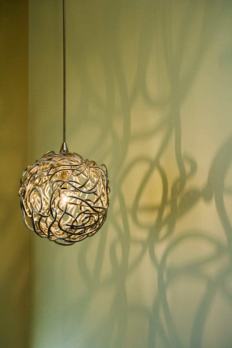 Artistic pendant light casting intricate shadows, part of a custom interior design by Thomas Buckborough & Associates in Acton, MA