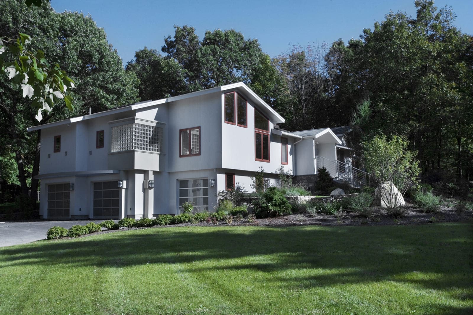 Front exterior of a modern home featuring a stylish glass and metal railing, designed by Thomas Buckborough & Associates in Acton, MA
