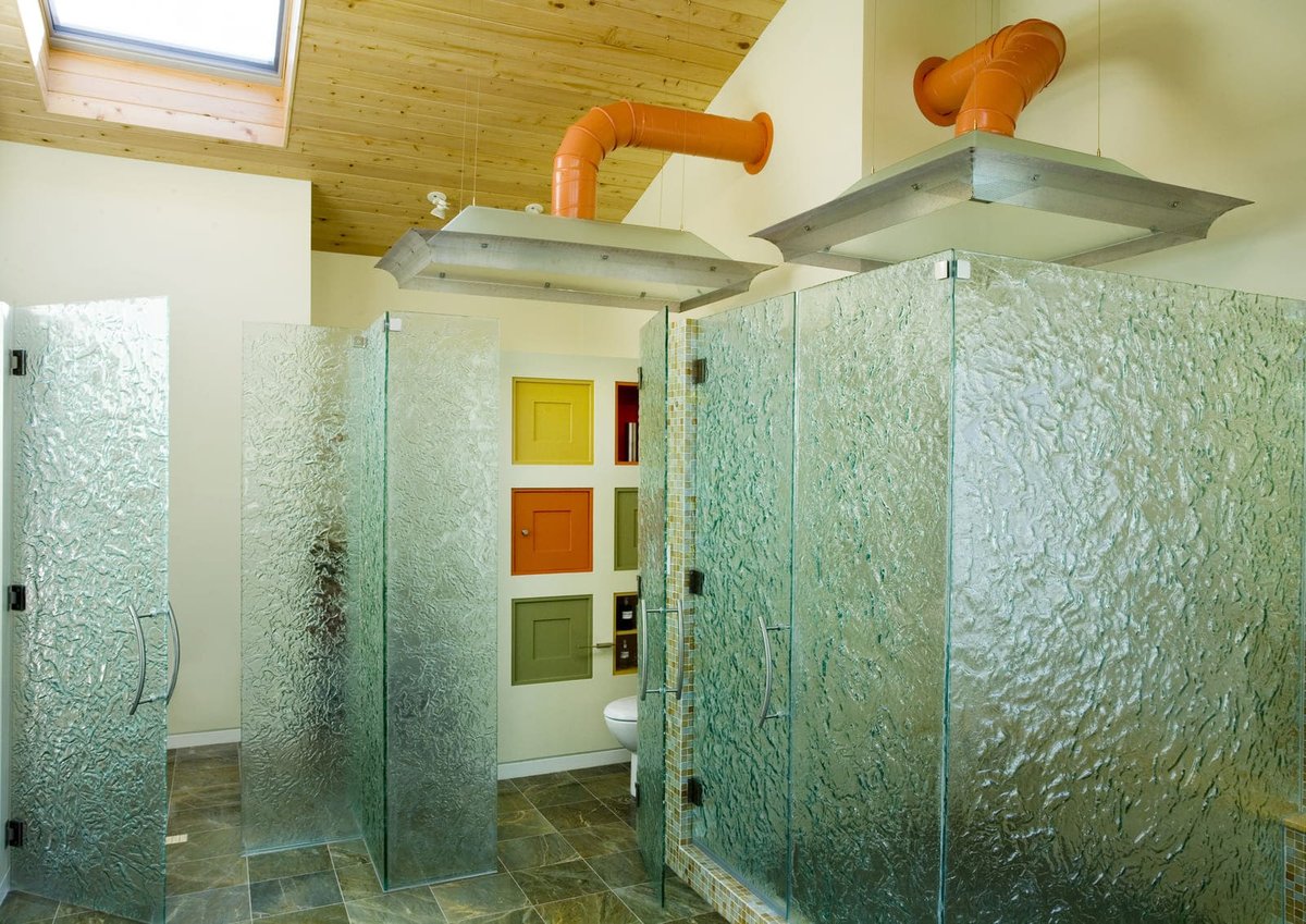 Stylish bathroom with frosted glass showers and modern fixtures, designed by Thomas Buckborough & Associates in Acton, MA