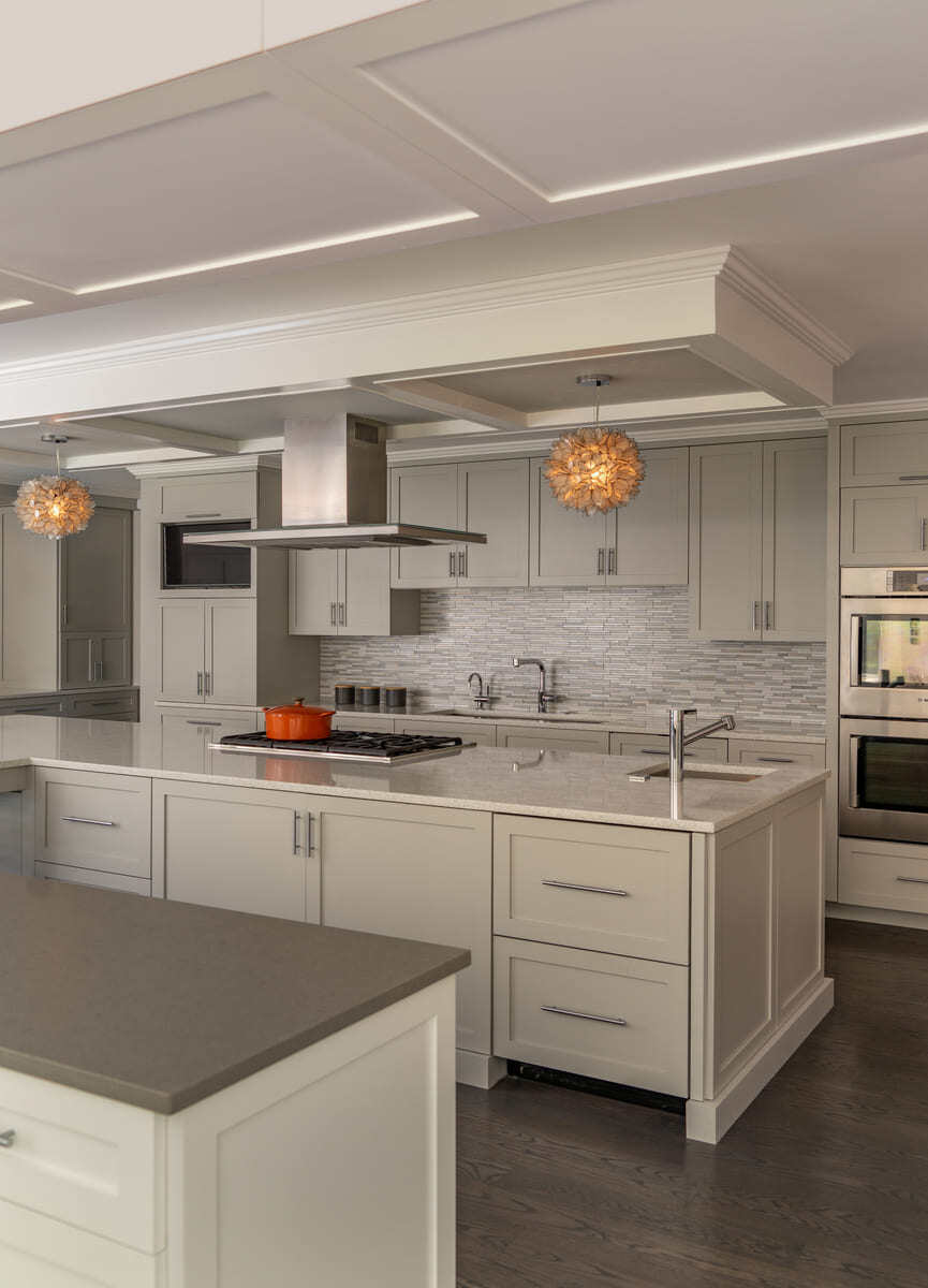 A stylish kitchen remodel with gray cabinetry, stainless steel appliances, and a modern backsplash by Thomas Buckborough & Associates in Acton, MA