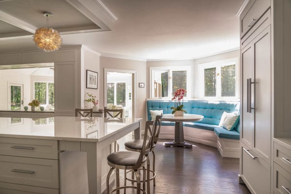 Bright breakfast nook with a custom turquoise banquette, round table, and stylish pendant lighting in a home renovation by Thomas Buckborough & Associates in Acton, MA