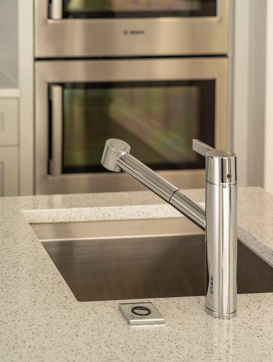 Close-up of a modern stainless steel kitchen sink with a sleek faucet in an Acton, MA, remodel by Thomas Buckborough & Associates