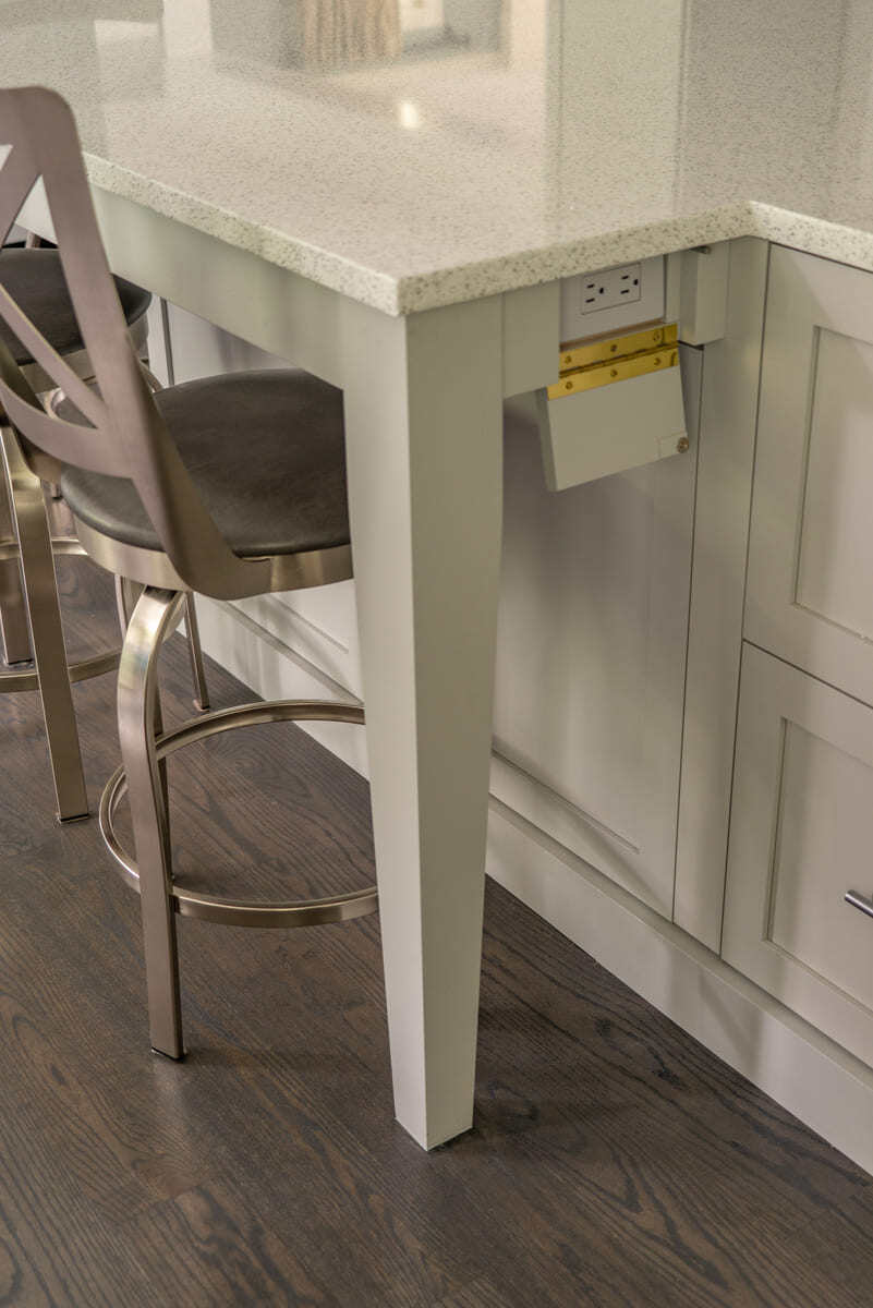Discreet pop-out power outlet integrated into a kitchen island for convenience, designed by Thomas Buckborough & Associates in Acton, MA
