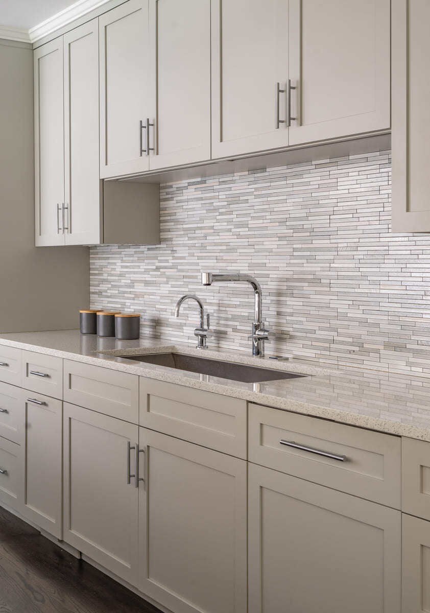 Elegant kitchen with a custom backsplash and a deep stainless steel sink, designed by Thomas Buckborough & Associates in Acton, MA