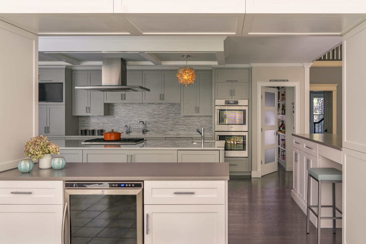 Modern kitchen featuring a sleek tile backsplash, a high-end range hood, and custom cabinetry, designed by Thomas Buckborough & Associates in Acton, MA