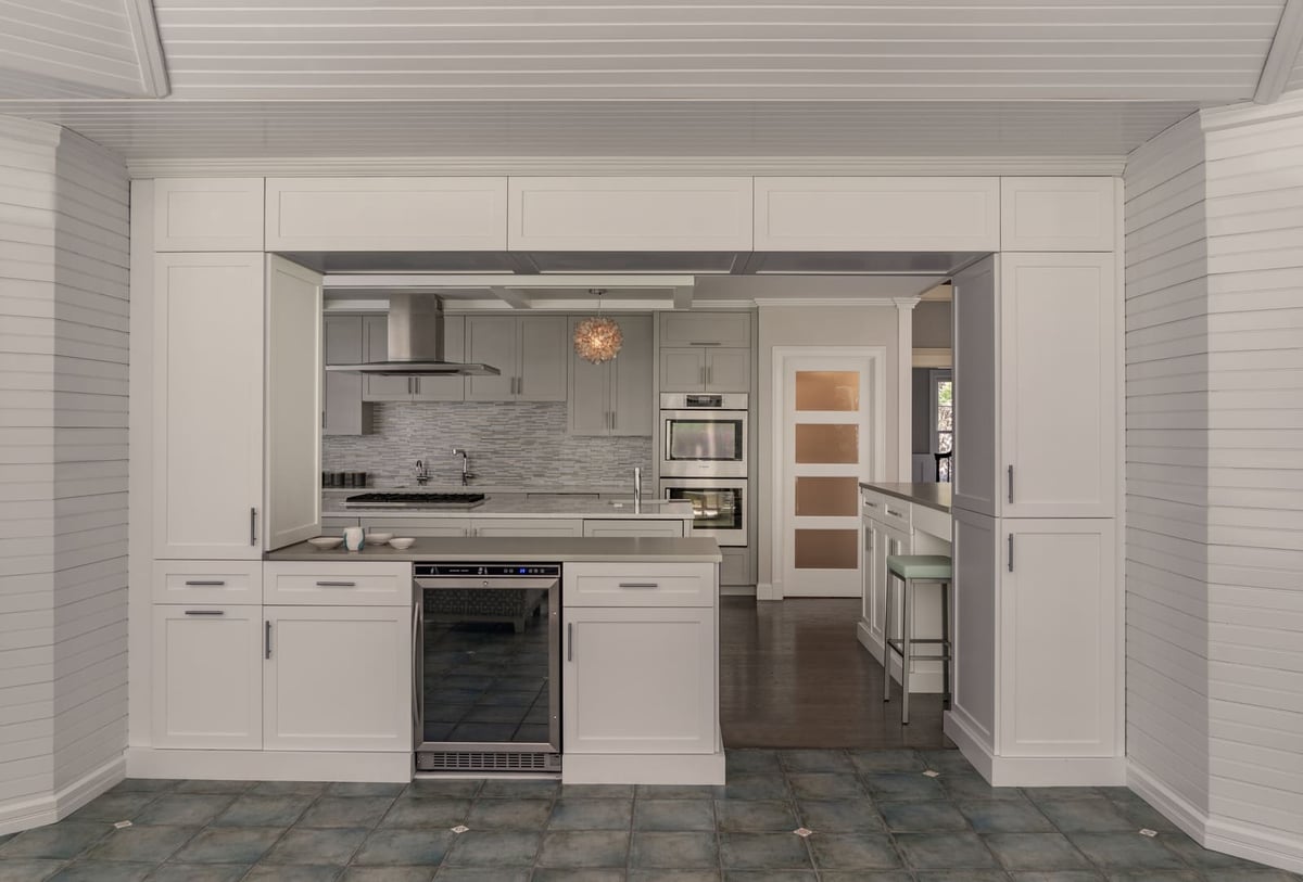 Transitional-style kitchen with open shelving, a center island, and elegant pendant lighting in this Acton, MA, remodel by Thomas Buckborough & Associates