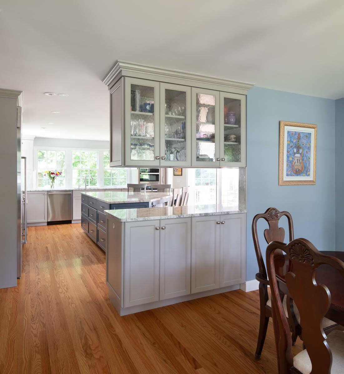 A beautifully remodeled kitchen in Acton, MA, featuring glass-front cabinets, marble countertops, and ample storage space