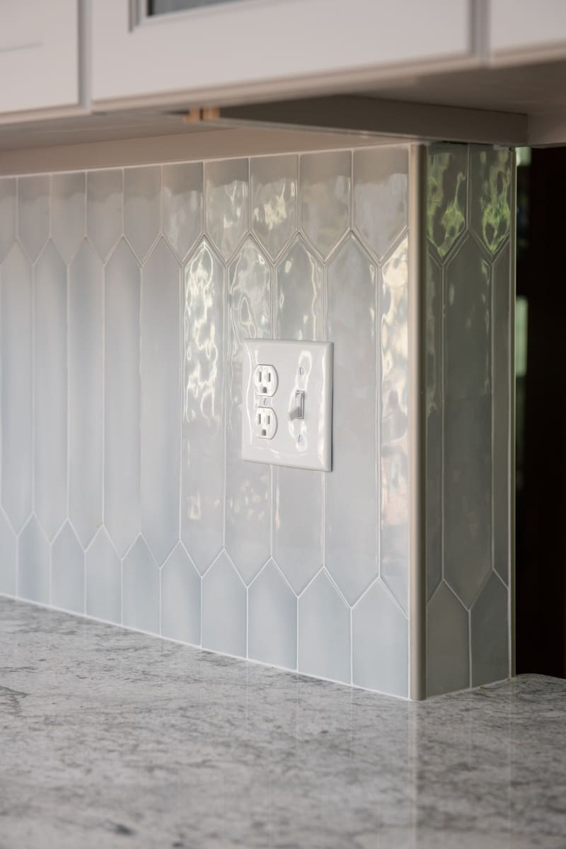A close-up of the backsplash and electrical outlet in a stylishly renovated kitchen by Thomas Buckborough & Associates