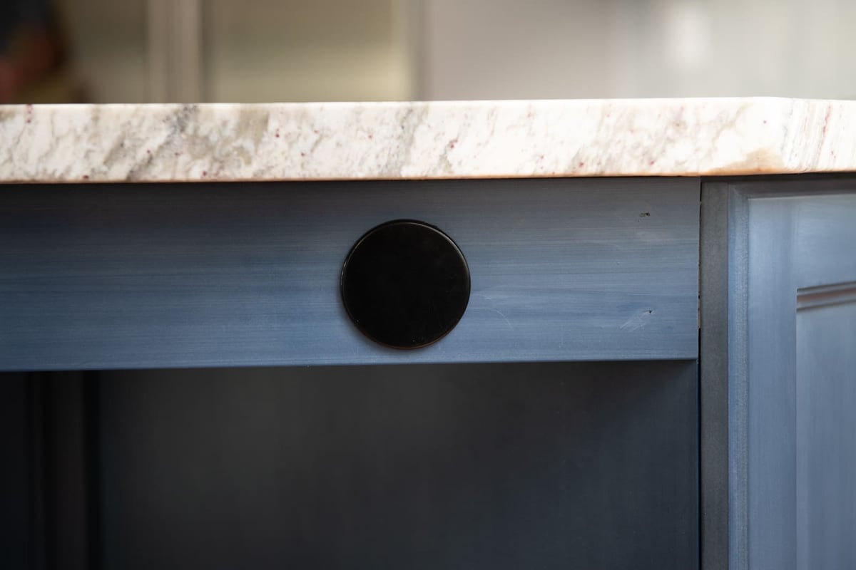 A modern kitchen island with a built-in outlet covered with a sleek black cap, part of a remodel in Acton, MA
