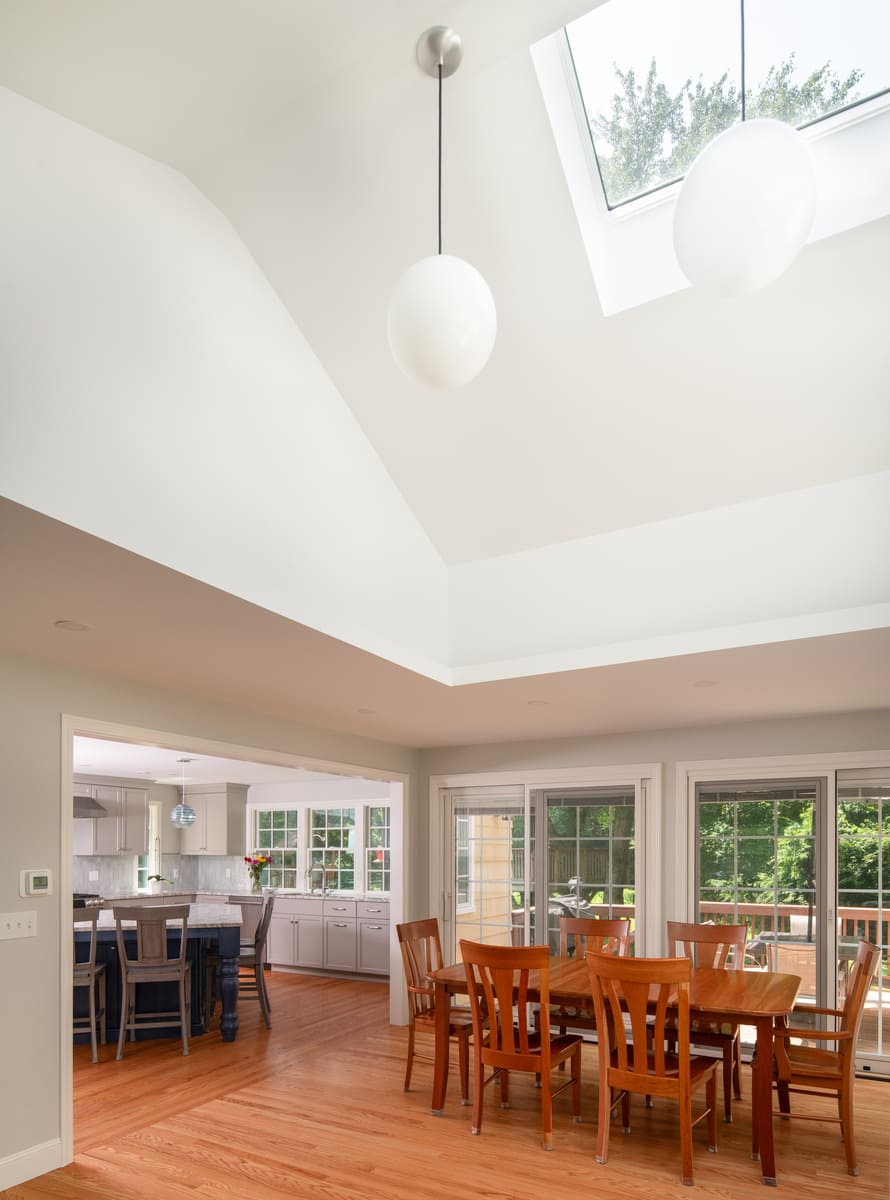 A modern living space remodel in Acton, MA, featuring vaulted ceilings, large skylights, and a cozy marble fireplace by Thomas Buckborough & Associates