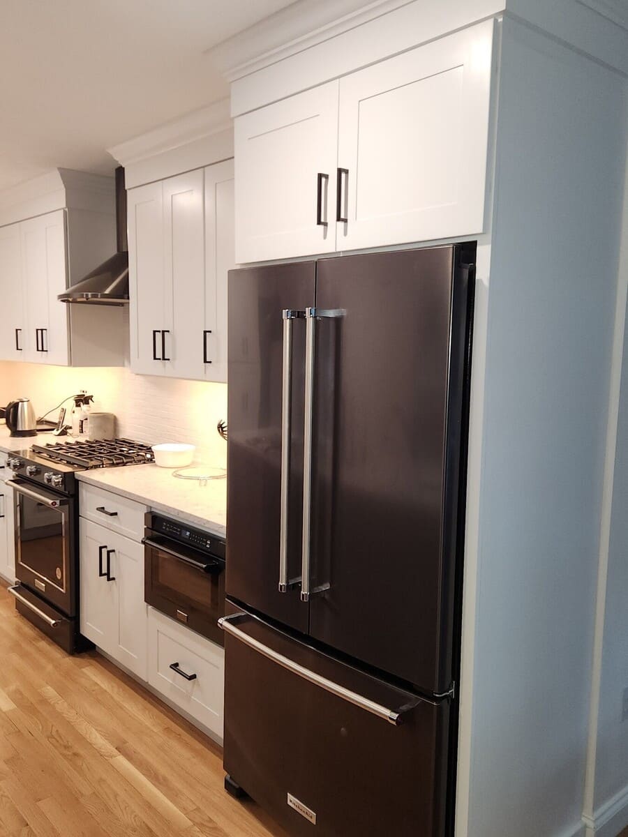Custom kitchen featuring a built-in refrigerator surrounded by white shaker cabinets and black hardware in a Sasot Rendo Remodel