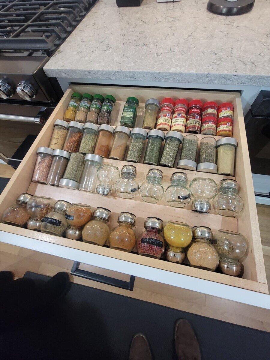Custom spice drawer with labeled glass jars and tiered organization in a modern kitchen remodel in Acton, MA by Thomas Buckborough & Associates