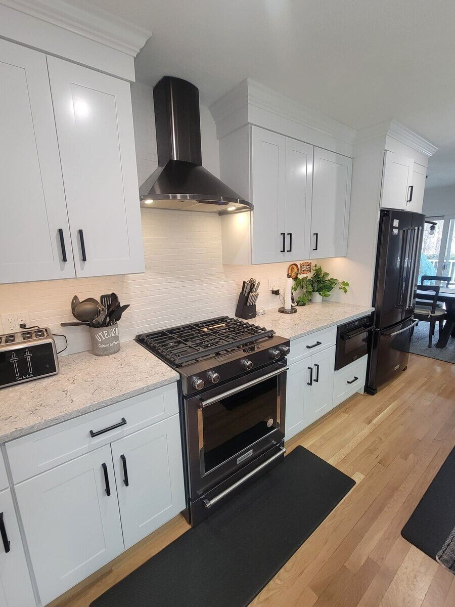 High-end kitchen remodel featuring a black gas range, modern white cabinetry, and a functional workspace by Thomas Buckborough & Associates