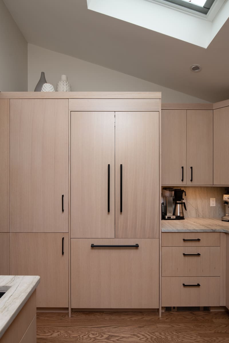 Custom-built refrigerator cabinetry blending seamlessly with kitchen design in a Shea home remodel by Thomas Buckborough & Associates in Acton, MA