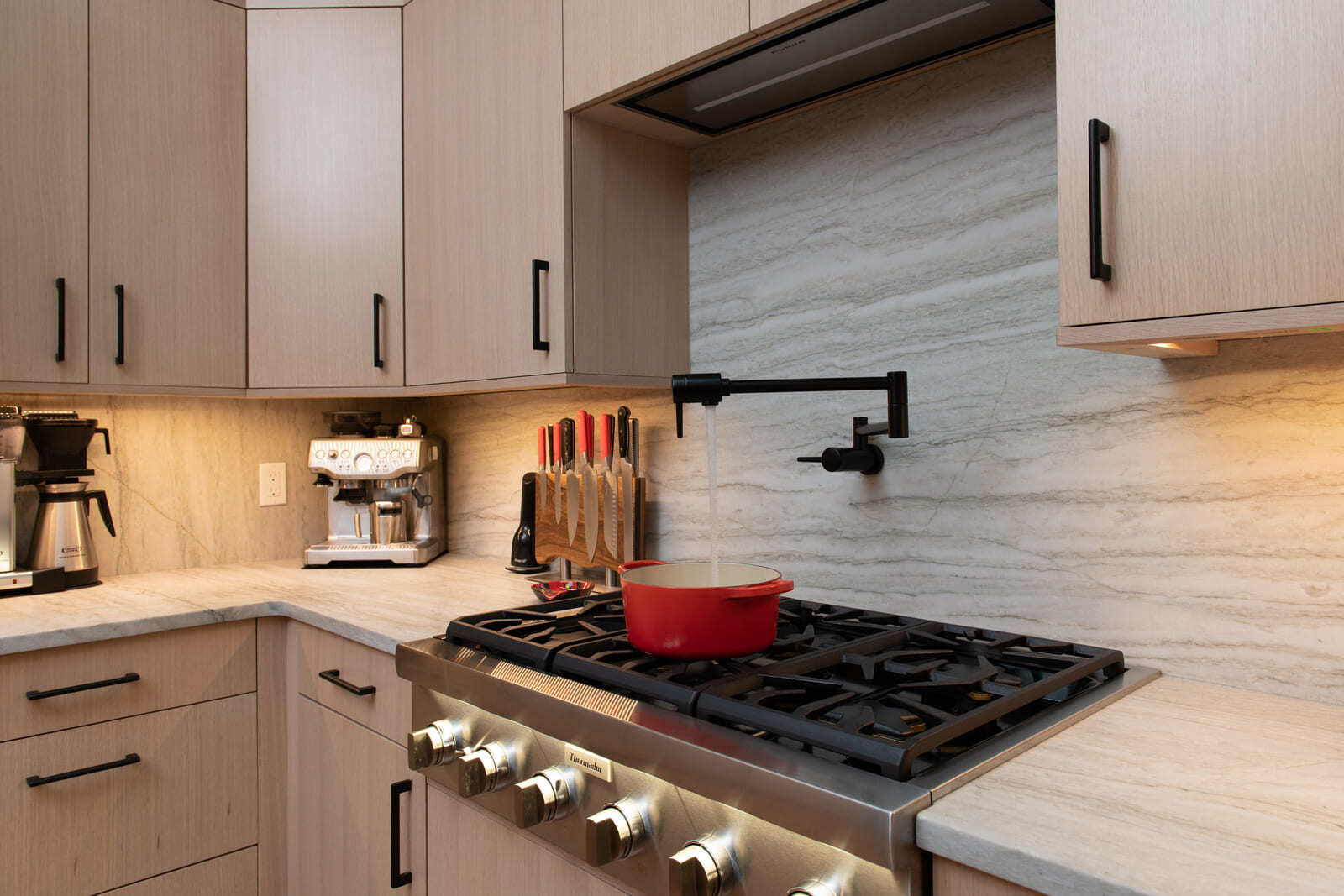 Pot filler faucet over a professional-grade gas stove in a Shea home remodel by Thomas Buckborough & Associates in Acton, MA