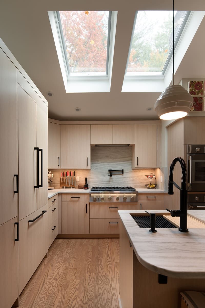 Stylish kitchen remodel with skylights and a modern island in a Shea home by Thomas Buckborough & Associates in Acton, MA
