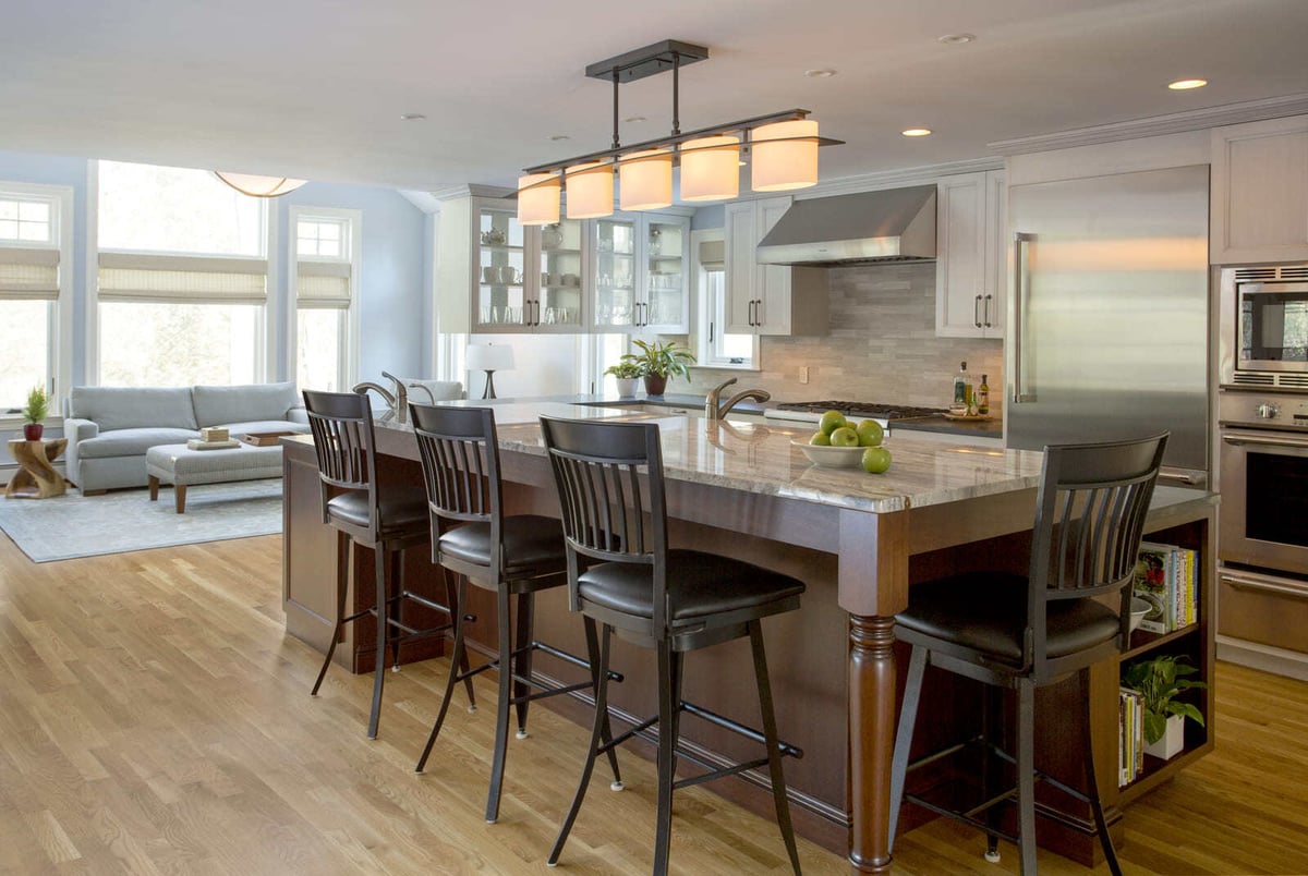 Bright and airy kitchen with a marble-topped island, modern appliances, and bar seating in a home remodel by Thomas Buckborough & Associates, Acton, MA