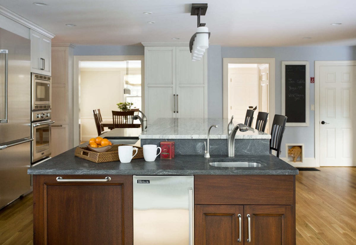 Functional kitchen space with warm wood accents, a built-in sink, and an eat-in bar area designed by Thomas Buckborough & Associates, Acton, MA