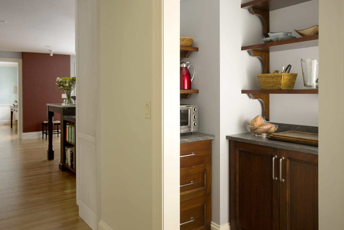 Well-organized pantry with dark wood cabinets and floating shelves in a kitchen renovation by Thomas Buckborough & Associates in Acton, MA