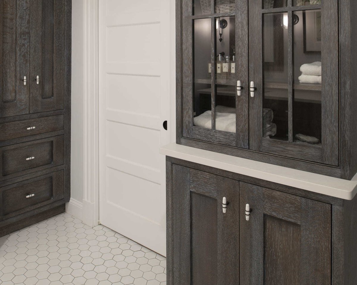 Custom bathroom cabinetry featuring dark wood tones, shaker-style doors, and elegant hardware in an Acton, MA home renovation