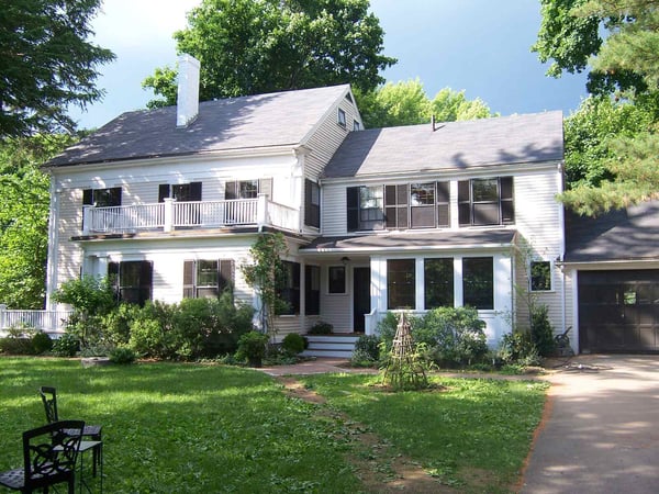 Elegant colonial-style home with a second-floor balcony and lush landscaping, designed by Thomas Buckborough & Co. in Harvard, MA