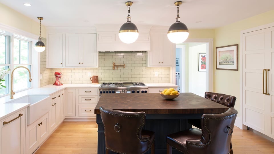 Kitchen renovation in greater boston with custom lighting, white cabinets, and gold fixtures