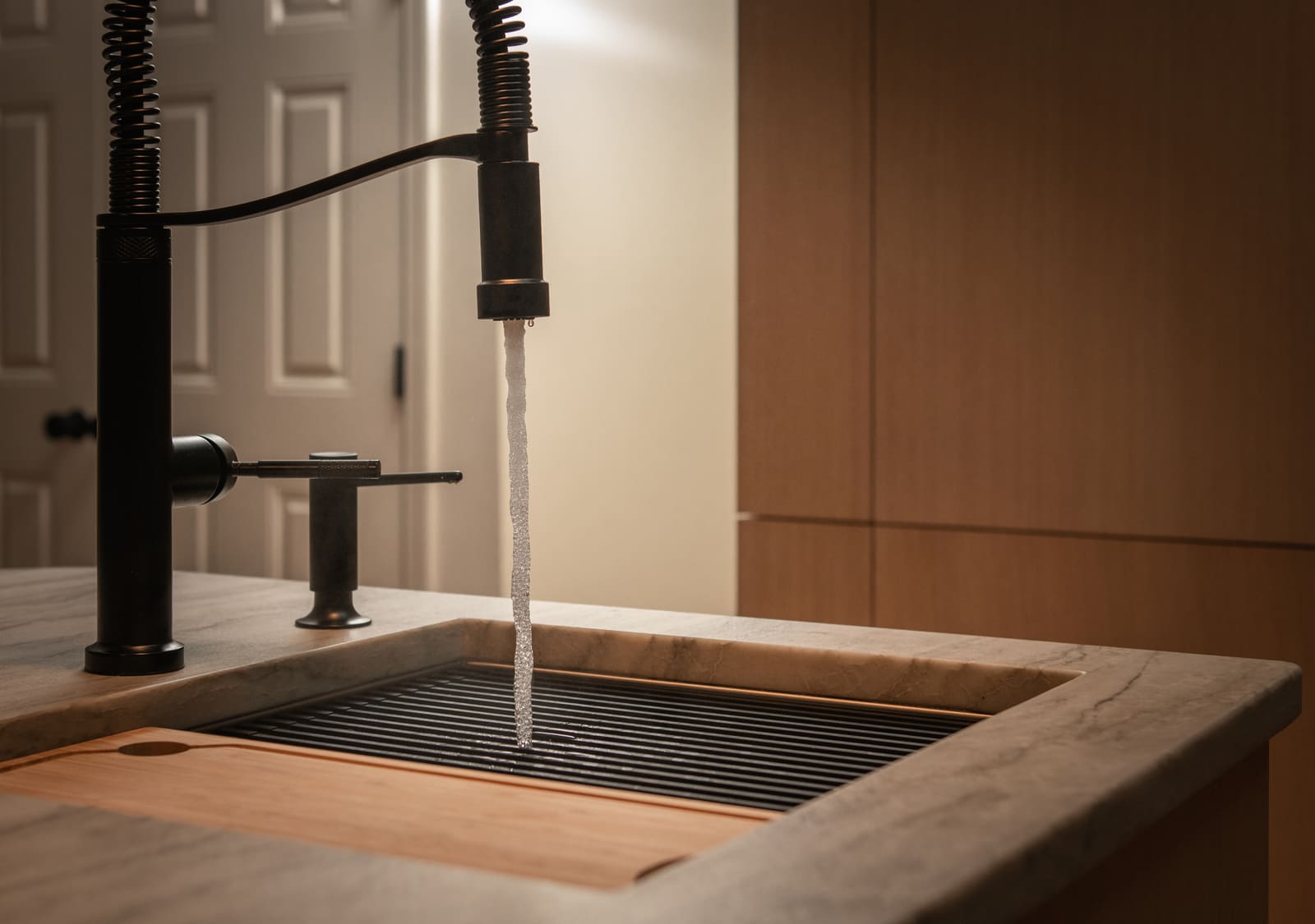 Close-up of a modern black kitchen faucet with running water in a Shea home remodel by Thomas Buckborough & Associates in Acton, MA