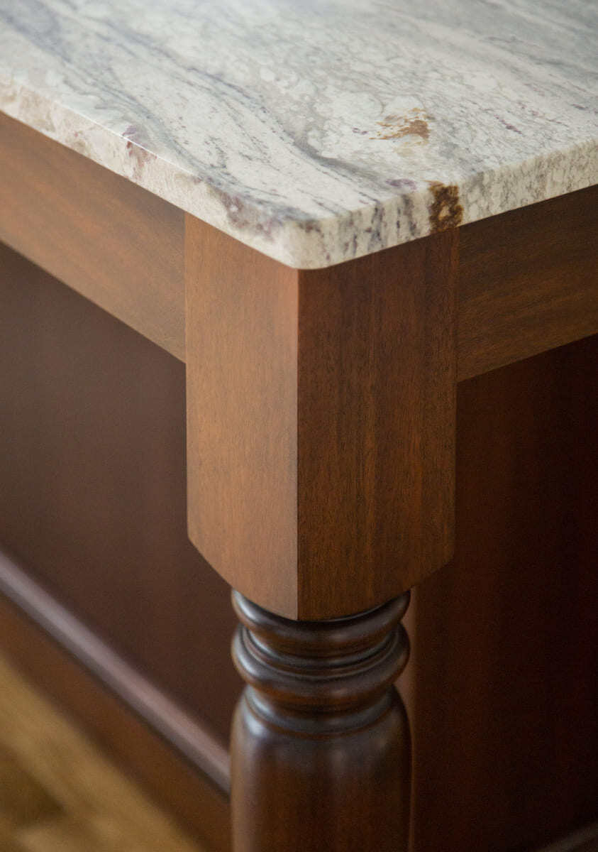 Close-up of a luxurious granite countertop with rich wood cabinetry in a custom kitchen remodel by Thomas Buckborough & Associates, Acton, MA